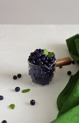 Fresh forest blueberries in a ladle with wooden handle on a white background. Close up.