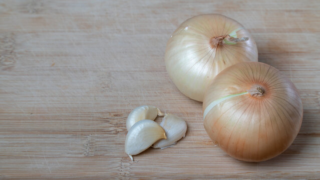 Bulbs in husks and cloves of garlic on a wooden background vegetables