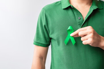 Hand holding green Ribbon for Liver, Gallbladders, bile duct, cervical, kidney Cancer and Lymphoma Awareness month. Healthcare and world cancer day concept