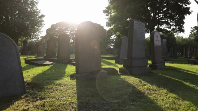 Beautiful headstones in a cemetery at sunset with cinematic lens flare