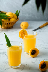 fresh apricot juice contains many vitamins, apricot and juice, green twigs in the background, cold drink, sweet summer cocktail 