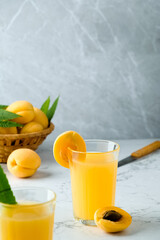 fresh apricot juice contains many vitamins, apricot and juice, green twigs in the background, cold drink, sweet summer cocktail 