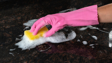 A woman's hand with sponge and foam cleans the dirty surface of the tile