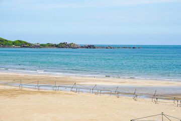 Taipei, Taiwan - July 20, 2022, calm beach by the sea, blue sea without people, sand, rocks
