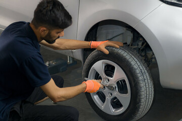 Fototapeta na wymiar Pakistani or Indian Mechanic fixing a tire in automobile garage