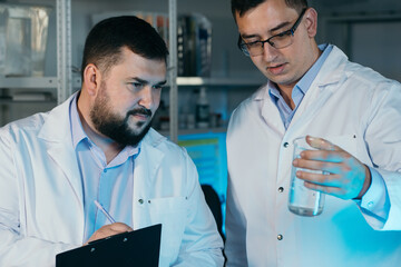 Young chemical technician checking liquid reagent in laboratory