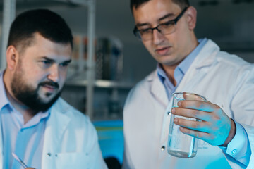 Young chemical technician checking liquid reagent in laboratory