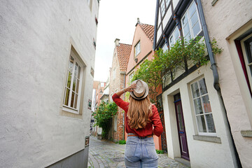 Attractive traveler woman walking in Schnoor neighborhood, Bremen, Germany - obrazy, fototapety, plakaty