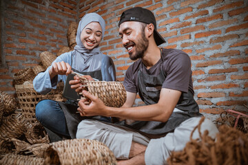 a woman in a hijab and a craftsman weaving water hyacinth handicrafts in a brick house