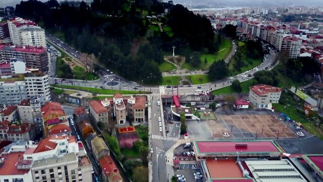 pull in drone shot of the city of Vigo in Galicia Spain flying over Mount De a Guia and colored buildings of the city center surrounded by nature, mountains and sea during a dark afternoon with clouds