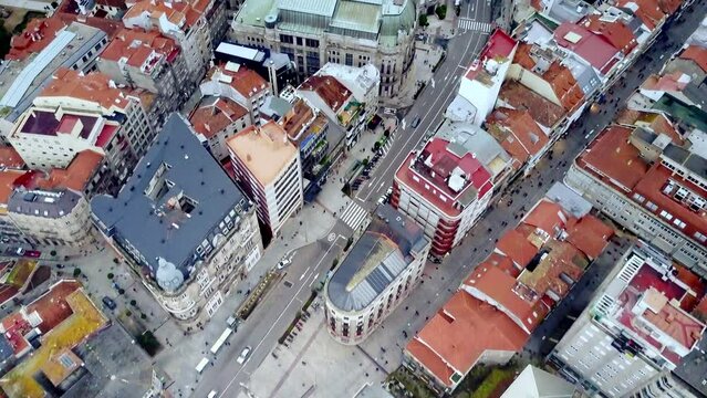 overhead drone shot of city of Vigo in Galicia Spain flying over the port and colored buildings of the city center surrounded by nature, mountains and sea during a dark afternoon with clouds and rainy