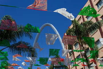 low view of tijuana mexico street with colorful party decorations with view to the arch
