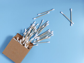 Cotton swabs made of bamboo in a cardboard box. Top view, blue background