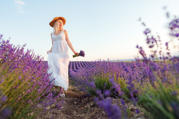 Young woman in long white dress standing in lavender field