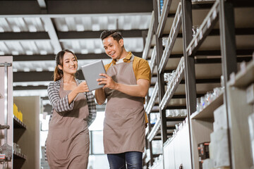 Young asian couple wearing apron using digital pad in houseware store