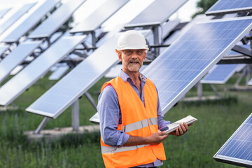 Closeup to the camera great looking mature man engineer and his team at photovoltaic solar farm...