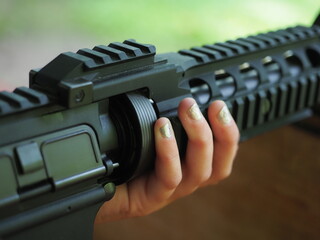 The barrel of a gun is held by a child in his hands, aims at the target