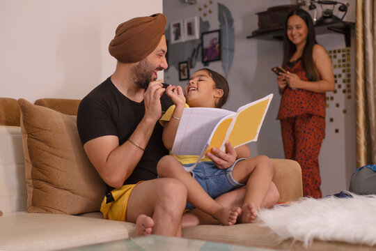 Father helping his daughter with homework while mother standing away