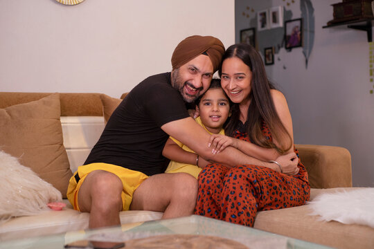 Portrait of happy Sikh family sitting on sofa in living room