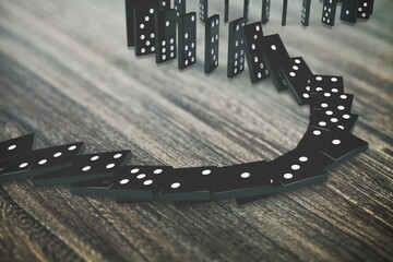 Black dominoes chain on a dark table. Domino effect concept