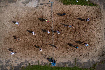 Aerial top down view of people playing volleyball outdoor. People shadows on the sand. Team game on the nature at summer