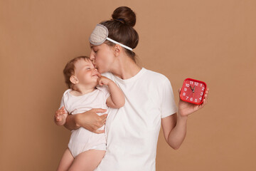Horizontal shot of attractive woman wearing white t shirt and blindfold holding baby daughter and...