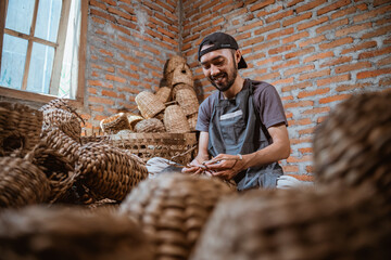 water hyacinth craftsman sitting weaving making souvenirs in a room full of woven baskets