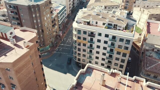 Drone shot of driving cars on junction surrounded by high-rise buildings during summer - Caravaca de La Cruz,Spain