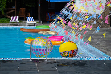 Inflatable circles and balls floating in an empty swimming pool. Summer vacation or beach relax concept with copy space.