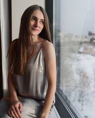 Young woman resting at hotel, sitting on the window sill enjoying beautiful view