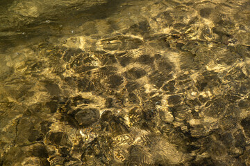 Water mountain river texture. Full frame. Fashionable light beige iridescent color of pure water. Iridescent sun and stones. Abstract natural background. Layout for wallpapers, postcards, banners.