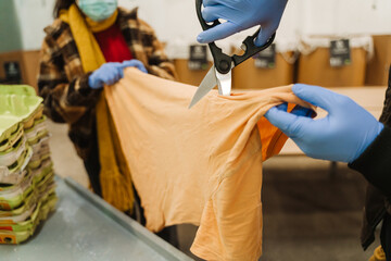 Hands in gloves cutting cloth at garbage recycling station