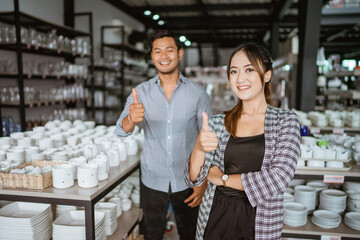 Beautiful asian woman smiling while standing with thumbs up in houseware store