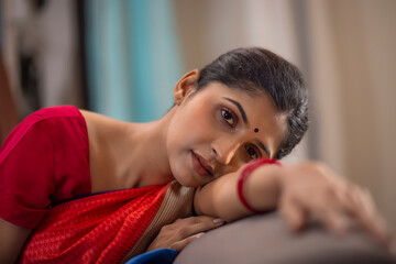 Close-up portrait of a young woman leaning on sofa
