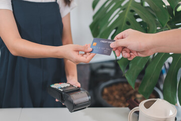 Customer using credit card for payment to owner at cafe restaurant, cashless technology and credit card payment concept