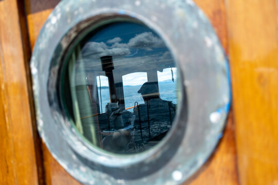 View of captain in hat through porthole window on wooden ship