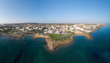 Aerial bird's eye view Pernera beach Protaras, Paralimni, Famagusta, Cyprus. The tourist attraction golden sand bay with sunbeds, water sports, hotels, restaurants, people swimming in sea from above. 