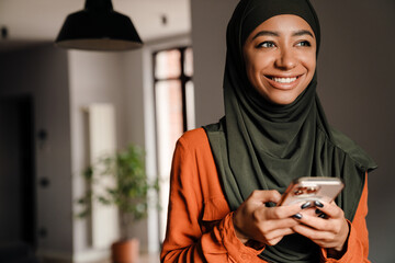 Young beautiful smiling woman in hijab with phone