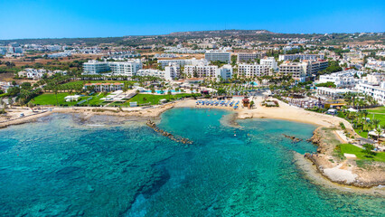 Aerial bird's eye view Pernera beach Protaras, Paralimni, Famagusta, Cyprus. The tourist attraction golden sand bay with sunbeds, water sports, hotels, restaurants, people swimming in sea from above. 