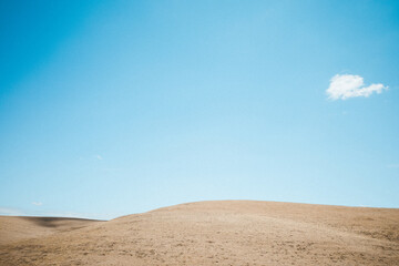 Bare drought stricken hills with one solitary cloud and shadow in central California in the middle of nowhere