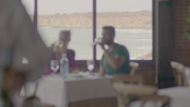 4K SlowMo - Young couple (20-25 years old) having a date in a restaurant gazebo overlooking the beach - cuddling, eating assorted raw tuna, drinking wine, toasting