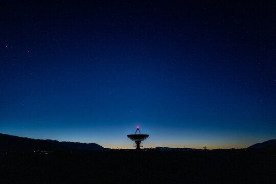 landscape wide shot of Owen Valley Radio Observatory under dark sky and crescent moon