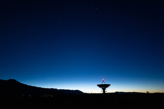 landscape wide shot of Owen Valley Radio Observatory under dark sky at dusk and crescent moon