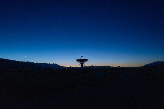 landscape wide shot of Owen Valley Radio Observatory under dark sky and crescent moon