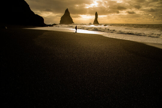 Traveler admiring volcanic black sandy beach landscape