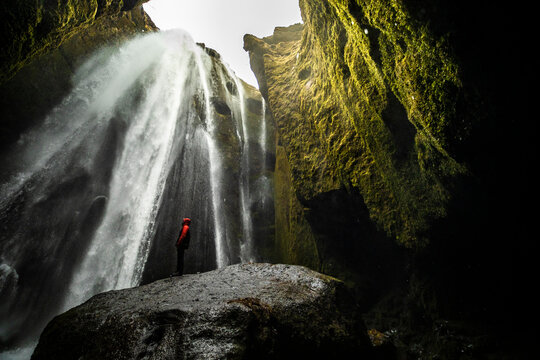 Anonymous Traveler Enjoying Energy Of Powerful Waterfall In Rocky Ravine