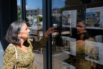 Vannes, France, 30 juillet 2022 : Femme regardant les annonces d'une agence immobiliere de la ville...