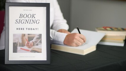 Male author signing a book for a female fan at a book launch.