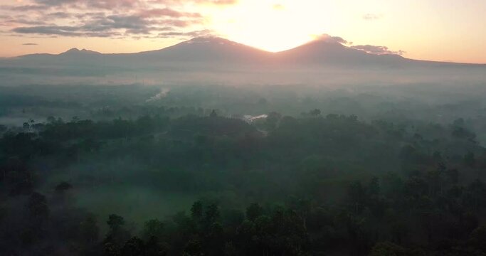 descending drone flight over the mountains surrounding the borobudur temple in indonesia at sunrise