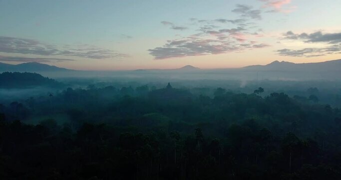 mystical drone flight over the nature and special colors in the sky around the majestic borobudur temple in indonesia at sunrise